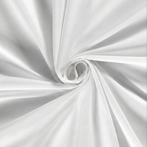 Pu&ograve; includere: Primo piano di un tessuto bianco, disposto in un motivo a spirale. Il tessuto ha una consistenza liscia e fluida, con ombre morbide e riflessi che ne esaltano le pieghe e le curve. L'effetto complessivo &egrave; di eleganza e fluidit&agrave;.
