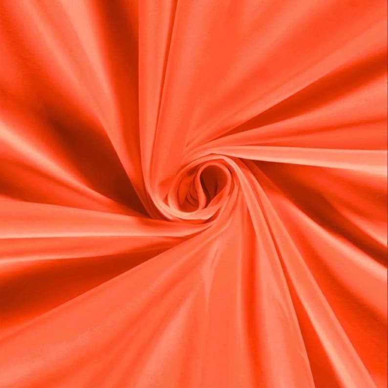 Pu&ograve; includere: Primo piano di un tessuto arancione vibrante, disposto a spirale. La trama liscia del tessuto e il gioco di luci e ombre creano un senso di profondit&agrave; e movimento. Il colore &egrave; una tonalit&agrave; calda e brillante.