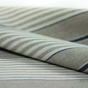 Pu&ograve; includere: Primo piano di un tessuto piegato con un motivo a righe in tonalit&agrave; beige e blu.