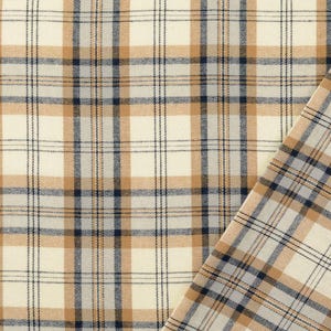 May include: Close-up of a plaid fabric with a cream-colored background and a grid pattern of tan and navy blue lines. A corner of the fabric is folded over, revealing the pattern on the reverse side. The fabric has a woven texture.