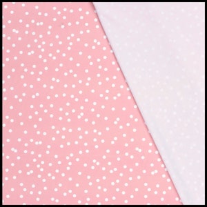 May include: Pink fabric with a white polka dot pattern. The fabric is folded in half, with the polka dot side facing up and the plain white side facing down.