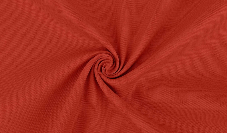 May include: Close-up of a red fabric with a textured surface. The fabric is folded and twisted, creating a swirling pattern.