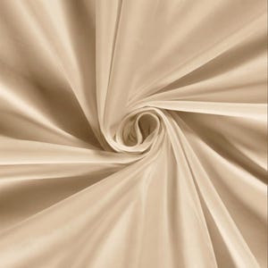 Pu&ograve; includere: Primo piano di un vortice di tessuto beige. Il tessuto ha una consistenza liscia e setosa con sottili riflessi e ombre. Le pieghe del tessuto creano un motivo a spirale, con il centro del vortice che appare pi&ugrave; chiaro.