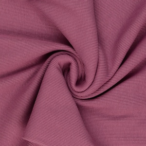 May include: Close-up of a folded fabric in a deep rose color. The fabric has a ribbed texture with vertical lines running across the material. The folds create shadows and depth, highlighting the texture and color of the fabric.