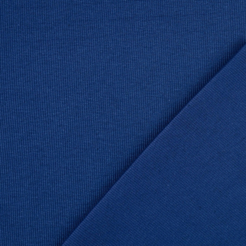 May include: A close-up shot of two pieces of blue fabric. The fabric on the left has a ribbed texture, while the fabric on the right is smooth. The colors are a deep, rich blue.