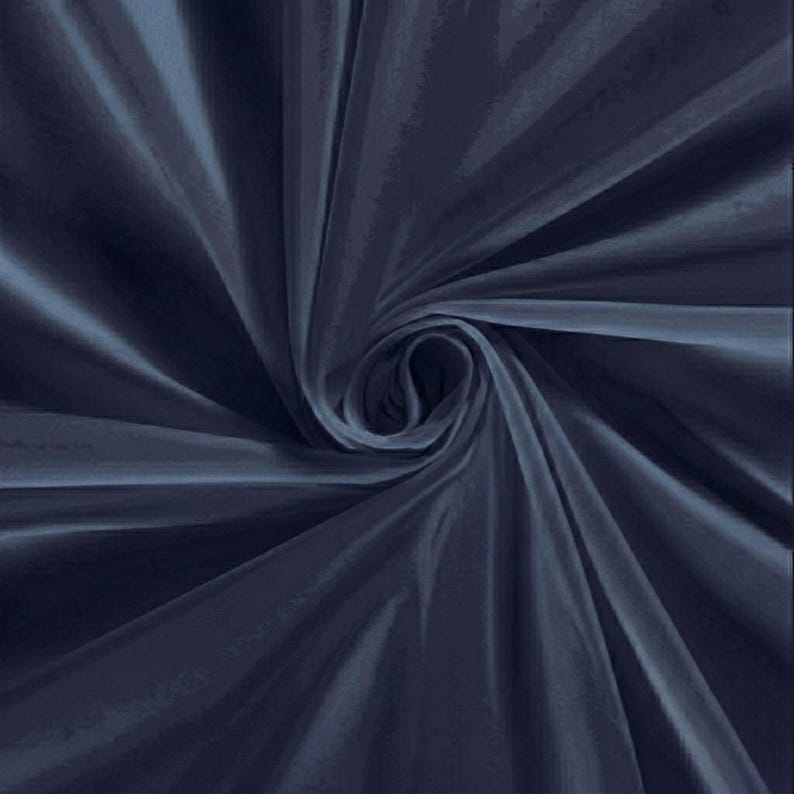 Pu&ograve; includere: Primo piano di un tessuto blu navy con un motivo a spirale. Il tessuto ha una consistenza setosa e liscia e riflette la luce, creando riflessi e ombre. Il tessuto &egrave; drappeggiato e piegato, creando un effetto a spirale.