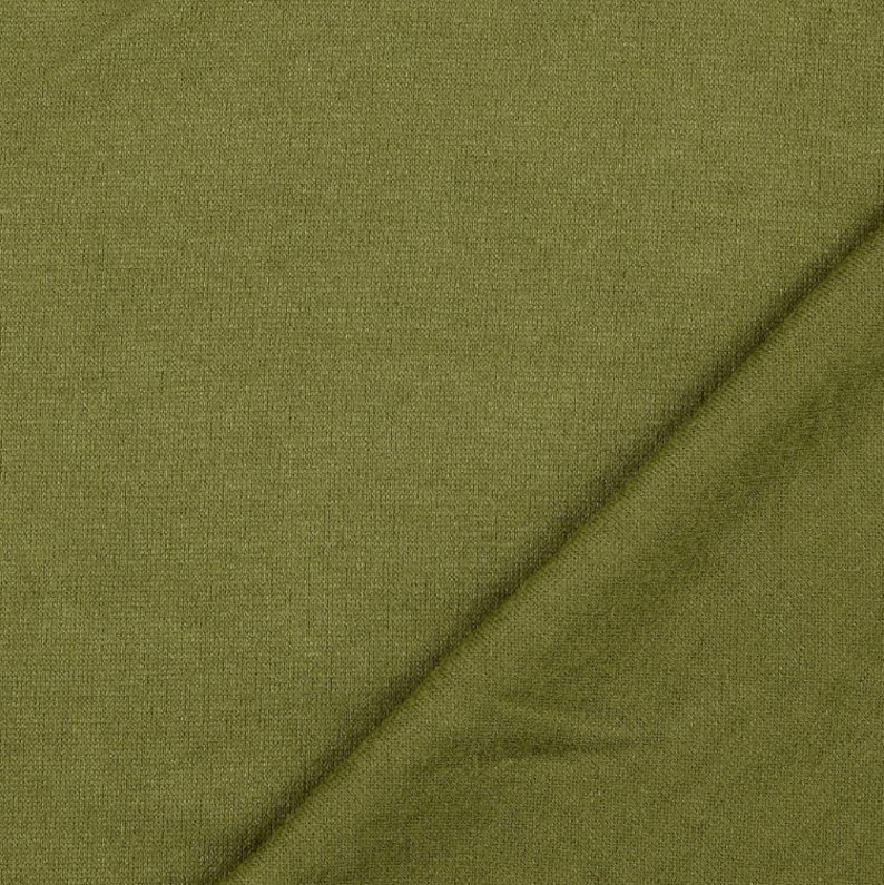 May include: Close-up of olive green fabric with a textured weave. The fabric is folded diagonally, creating shadows and highlighting the texture. The color is a muted, earthy tone, suitable for apparel or home decor.