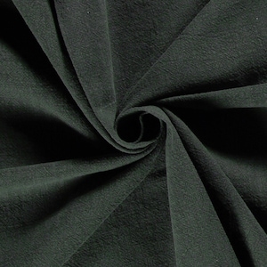 May include: Dark green fabric with a textured surface, arranged in a swirling pattern. The fabric's folds create shadows, highlighting the material's depth and texture. The overall appearance suggests a soft, flowing textile, suitable for clothing or home decor.