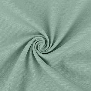 May include: A close-up of a soft, light green fabric with a textured surface. The fabric is folded and twisted, creating a swirling pattern.