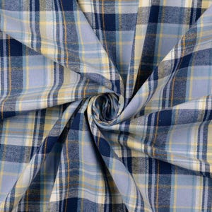May include: Close-up of a blue, yellow, and white plaid fabric. The fabric is folded and swirled, showcasing the pattern's intricate design. The plaid features varying shades of blue, with yellow and white accents, creating a visually appealing textile.