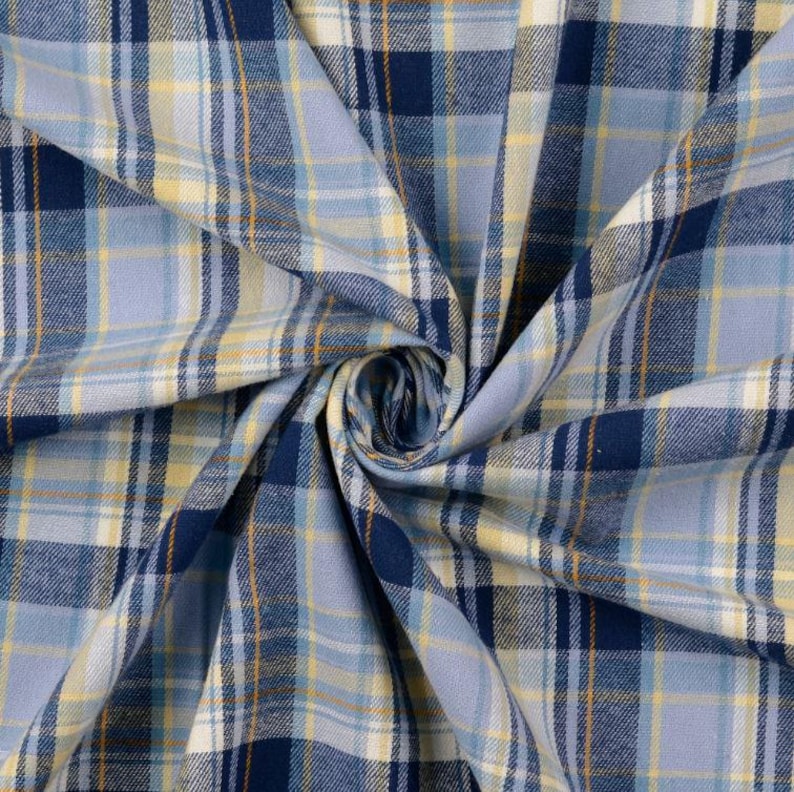 May include: Close-up of a blue, yellow, and white plaid fabric. The fabric is folded and swirled, showcasing the pattern's intricate design. The plaid features varying shades of blue, with yellow and white accents, creating a visually appealing textile.