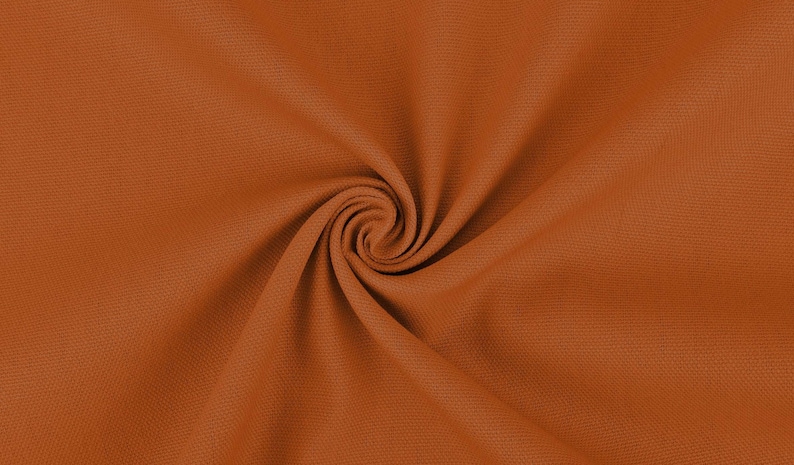 May include: Close-up of a rust-colored fabric with a textured surface. The fabric is folded and twisted, creating a swirling pattern.