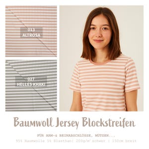 Könnte beinhalten: Eine Frau trägt ein kurzärmeliges, hellrosa und weiß gestreiftes T-Shirt. Das Bild zeigt auch zwei Stoffmuster: eines in hellrosa und weißen Streifen, beschriftet mit "013 ALTROSA", und ein weiteres in grau-weißen Streifen, beschriftet mit "027 HELLES KHAKI". Der Text "Baumwoll Jersey Blockstreifen" steht unten.