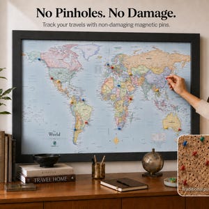 May include: A framed world map with a light blue ocean and multicolored landmasses, featuring magnetic pins. Text reads: No Pinholes. No Damage. Track your travels with non-damaging magnetic pins. An inset shows a cork surface with traditional push-pins.