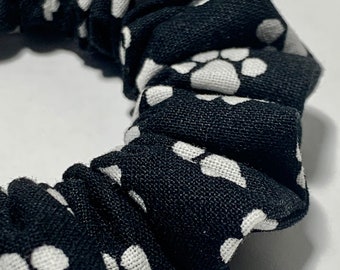 May include: Black and white scrunchie with a paw print pattern.