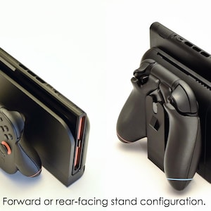 May include: Black gaming console stand with attached controllers, shown in forward and rear-facing configurations. The stand has a sleek design with red and blue accents. The text at the bottom reads "Forward or rear-facing stand configuration."