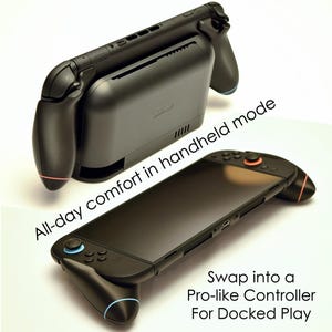 May include: Black handheld gaming device with attached controllers. The device is shown in two configurations, one for handheld mode and another for docked play. Text on the image reads "All-day comfort in handheld mode" and "Swap into a Pro-like Controller For Docked Play."
