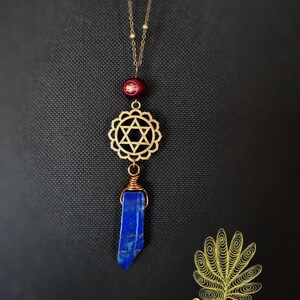 May include: Gold necklace with a red bead, a gold star of David charm, and a blue lapis lazuli pendant.