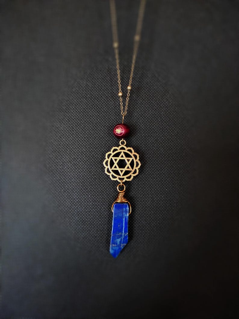 May include: A gold necklace with a red bead, a gold star of David charm, and a blue lapis lazuli stone pendant.