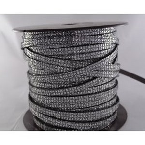 May include: A spool of silver rhinestone ribbon. The ribbon is tightly wound around a black spool. The ribbon is a flat, flexible material covered in small, sparkling rhinestones. The ribbon is a decorative trim.