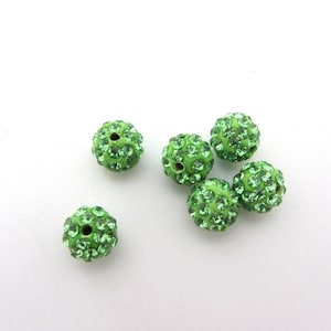 Può includere: Sei perline rotonde verdi ricoperte di piccoli strass verdi. Le perline hanno un diametro di circa 1 cm.