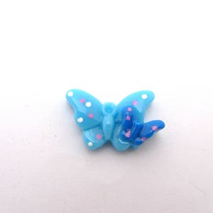 Une demi perles papillon en résine bleu avec des petits pois