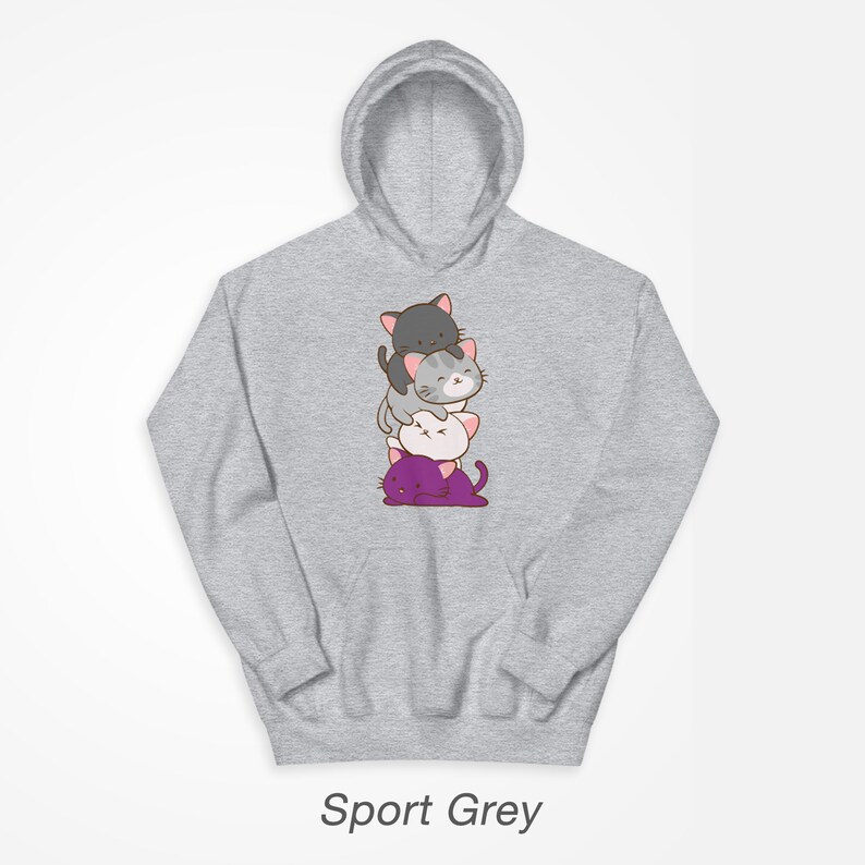 Puede incluir: Una sudadera con capucha gris con una pila de cuatro gatos de dibujos animados en la parte delantera. Los gatos est&aacute;n apilados uno encima del otro, con el gato de abajo morado, el siguiente blanco, el siguiente gris y el gato de arriba negro. Todos los gatos tienen la nariz rosa y bigotes.