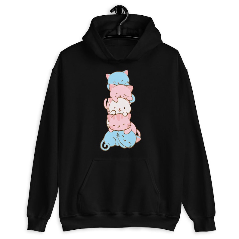 May include: Black hoodie with a stack of four cartoon cats in blue, pink, and white colors. The cats are stacked on top of each other, with the bottom cat's tail curled around the side.