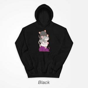 Puede incluir: Sudadera con capucha negra con un gr&aacute;fico de cuatro gatos de dibujos animados apilados. Los gatos son grises, blancos y morados.