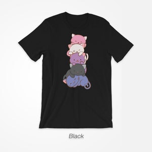 Pu&ograve; includere: T-shirt nera con un disegno di cinque gatti dei cartoni animati impilati, rosa, bianchi, viola e grigi. I gatti sorridono. La parola "Black" &egrave; stampata in basso sulla maglietta.