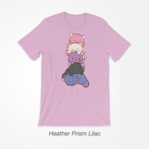 Pu&ograve; includere: T-shirt Heather Prism Lilac lilla chiaro con un disegno di cinque gatti dei cartoni animati impilati uno sull'altro. I gatti sono nei colori rosa, bianco, viola e nero. Il testo "Heather Prism Lilac" &egrave; in basso.