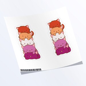 May include: Two stacks of five colorful cat stickers. Each stack is arranged from red to orange to white to purple to pink. The cats are all facing forward with their eyes closed and their mouths slightly open.