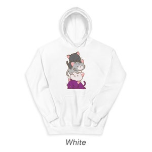Puede incluir: Sudadera con capucha blanca con un gr&aacute;fico de cuatro gatos de dibujos animados apilados. Los gatos son grises, blancos y morados.