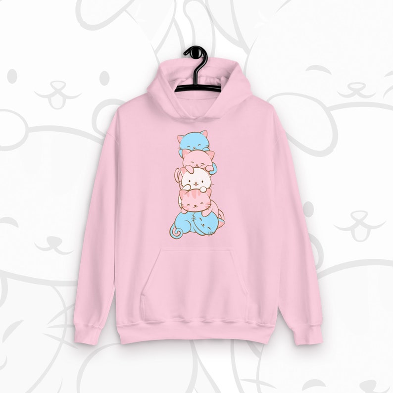 May include: Pink hoodie with a stack of four cartoon cats in different colors. The cats are stacked on top of each other, with the bottom cat lying down and the top three cats sitting up.