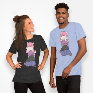 Pu&ograve; includere: Due persone indossano magliette con un disegno di gatti impilati. Il disegno presenta una pila di cinque gatti dei cartoni animati in rosa, bianco, viola, grigio e nero. Le magliette sono grigio melange e azzurro.
