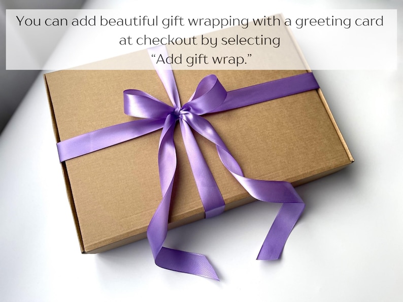 May include: A rectangular brown cardboard box tied with a smooth, shiny purple satin ribbon arranged in a bow. The text on the image reads: You can add beautiful gift wrapping with a greeting card at checkout by selecting Add gift wrap.