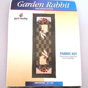 Può includere: Un kit di tessuto per un modello di runner da tavolo Garden Rabbit. Il design presenta un motivo a scacchiera con sagome di conigli e accenti floreali. Dimensioni: 35,56 cm x 101,6 cm. Il kit include il testo "Fabric Kit".