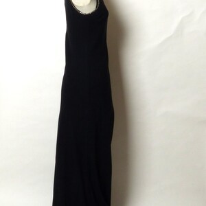 May include: A black sleeveless maxi dress with a beaded neckline. The dress is on a white background.
