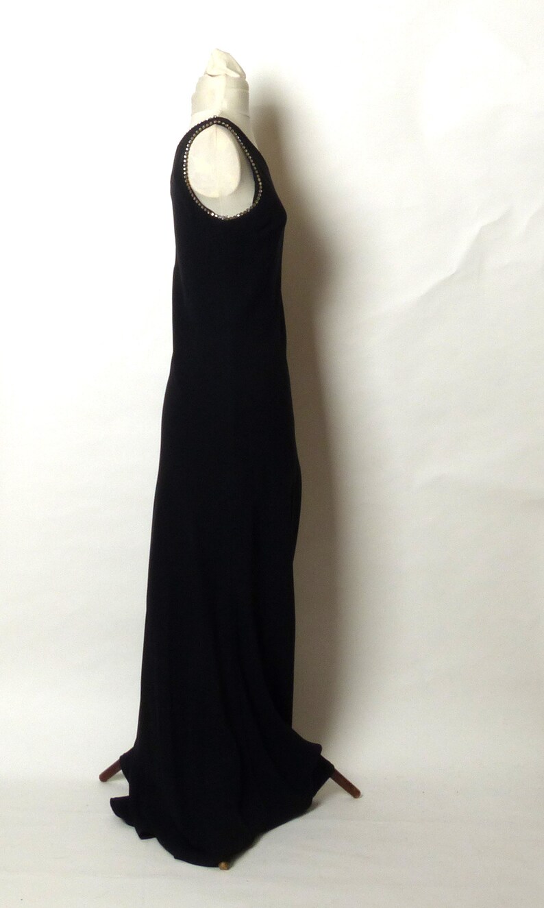 May include: A black sleeveless maxi dress with a beaded neckline. The dress is on a white background.