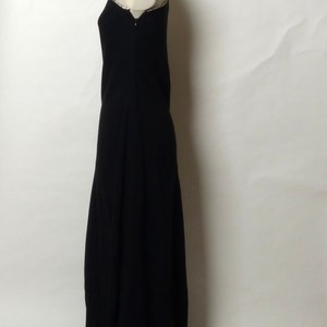 May include: A black floor-length dress with a beaded neckline. The dress is on a white mannequin.