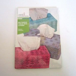 May include: A package of rectangle tissue box covers. The covers are in various colors, including red, blue, and purple, with floral and geometric patterns. The package has the text "ANITA GOODESIGN" and "RECTANGLE TISSUE BOX COVERS Projects Collection."