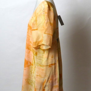 Puede incluir: Un vestido de manga corta con estampado abstracto en melocot&oacute;n y amarillo. El vestido tiene un escote en V y un corte holgado.