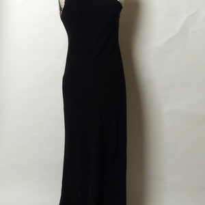 May include: A black one-shoulder evening gown with a beaded trim. The gown has a fitted bodice and a flowing skirt.