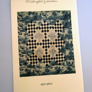 May include: A cream-colored brochure with the title "Midnight Garden" in elegant script. The brochure features a central design of black and white diamonds, with floral basket illustrations. The background has a blue and white landscape pattern. The code "MJP-QP02" is at the bottom.