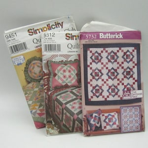 Pode incluir: Três padrões de acolchoado, dois da Simplicity e um da Butterick. Os padrões da Simplicity são para uma colcha e um travesseiro, e o padrão da Butterick é para uma colcha e dois travesseiros. Os padrões apresentam uma variedade de cores e desenhos, incluindo vermelho, azul, verde e branco.