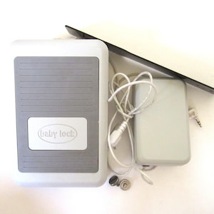 May include: A white and gray foot pedal with the text "Baby Lock" on it. The pedal is connected to a white power adapter with a black cord.