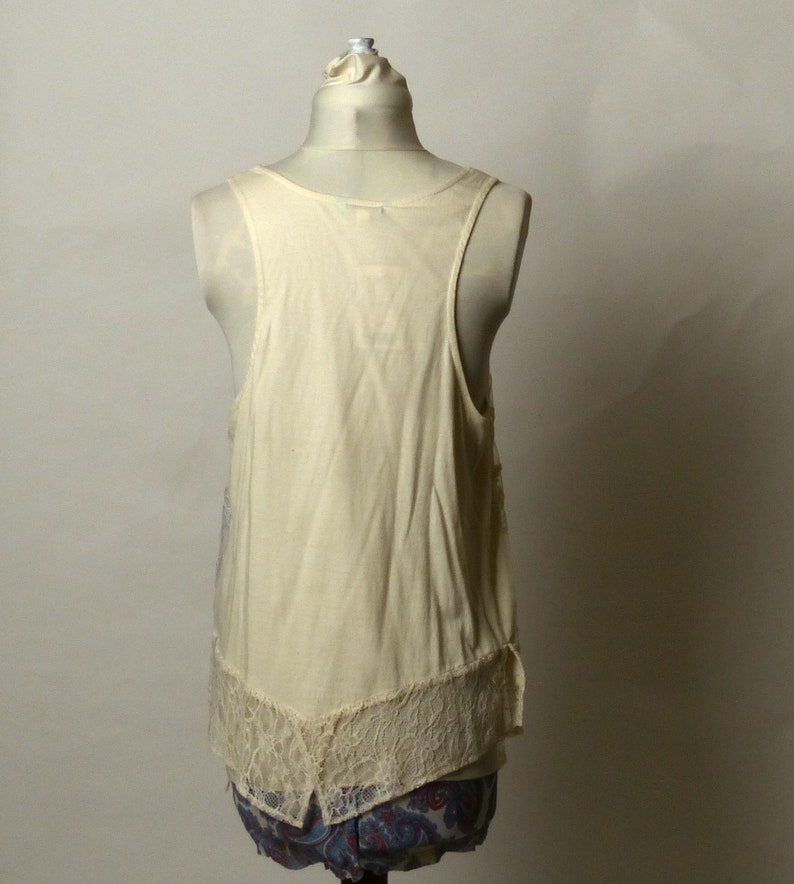 May include: A white sleeveless top with a lace trim. The top is on a white mannequin.