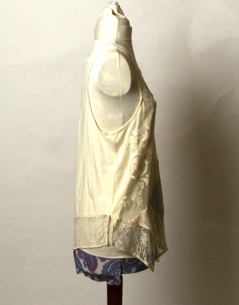 May include: A white sleeveless top with lace detailing and a paisley print on the bottom.