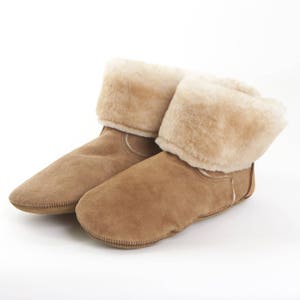 May include: A pair of brown suede slippers with a fold-over cuff of fluffy white sheepskin.