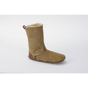 May include: A pair of brown suede sheepskin boots with a fur lining. The boots have a rounded toe and a flat sole.